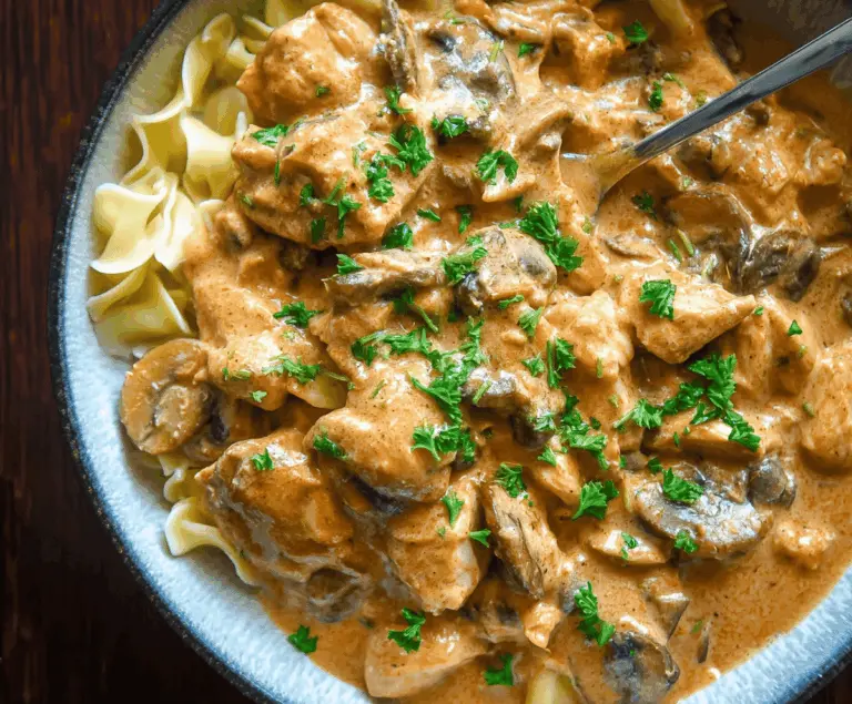 Creamy Chicken Stroganoff served over noodles with mushrooms and fresh herbs, perfect for a comforting dinner.