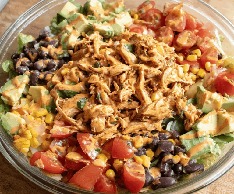 Fresh Southwest Chicken Salad featuring grilled chicken, mixed greens, corn, black beans, cherry tomatoes, shredded cheese, and a spicy southwest dressing in a bowl