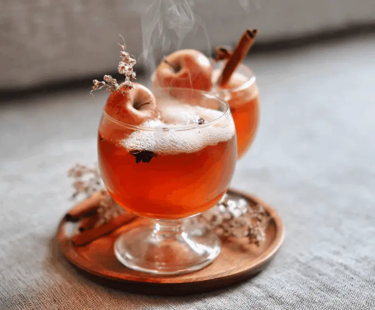 Spooky Poisoned Apple Cider in a haunted-themed mug with cinnamon sticks and apple slices for Halloween party drinks