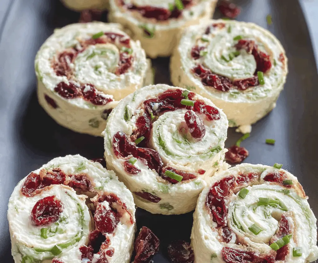 Cranberry and feta cheese pinwheels with cream cheese filling on a platter.
