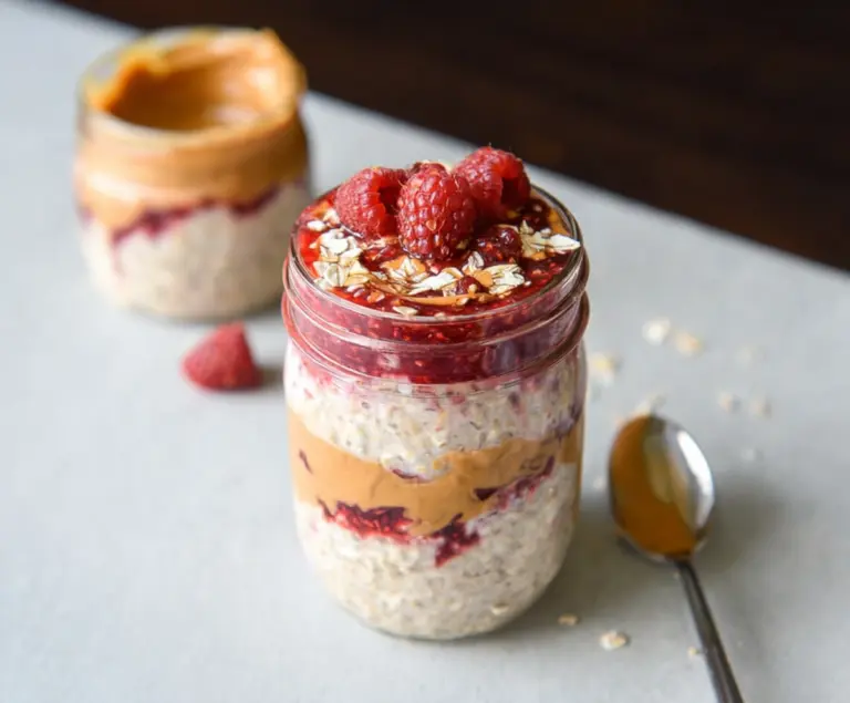 Creamy peanut butter and fruity jelly layered overnight oats in a glass jar for a healthy breakfast