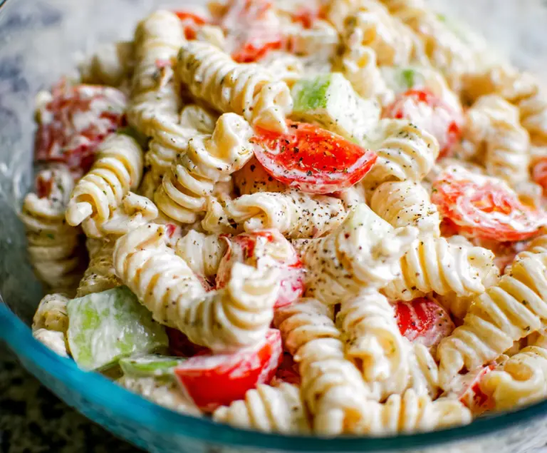 Creamy Pasta Salad with fresh vegetables and herbs in a white bowl, perfect for summer picnics.