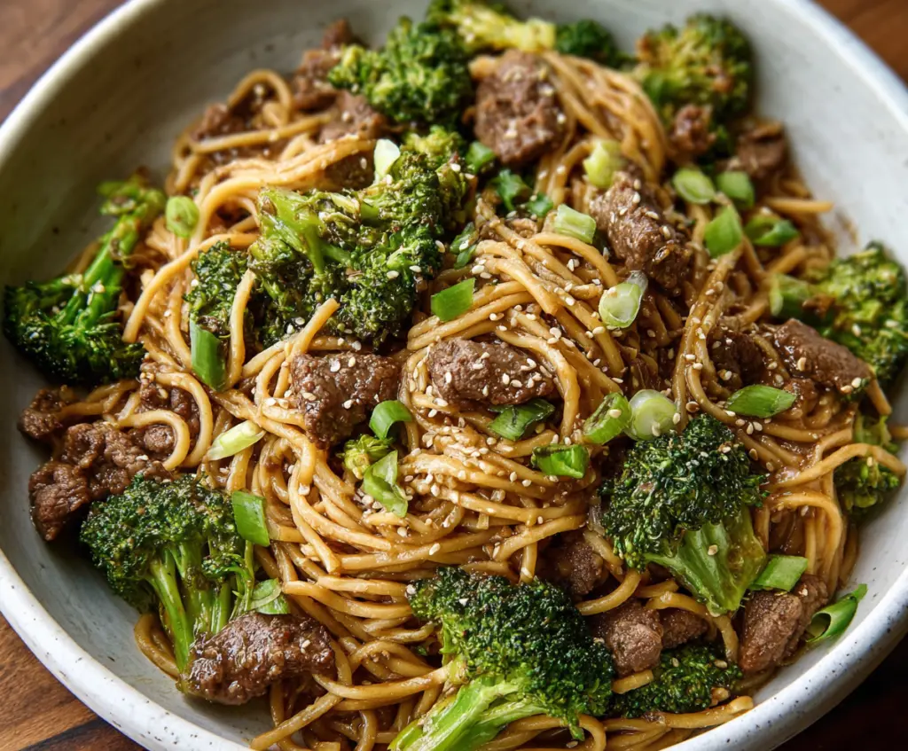 Delicious Garlic Ginger Beef and Broccoli Noodles served on a plate with fresh vegetables.