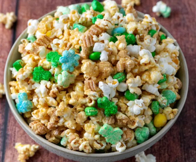 Colorful loaded leprechaun popcorn with rainbow sprinkles and marshmallows in a festive decorative bowl.