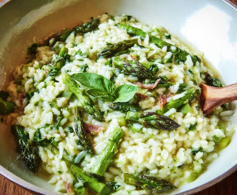 Creamy asparagus risotto garnished with fresh herbs and grated cheese on a rustic plate.