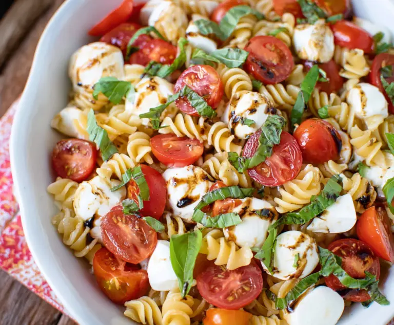 Fresh Caprese Pasta Salad with cherry tomatoes, mozzarella, basil, and balsamic glaze.