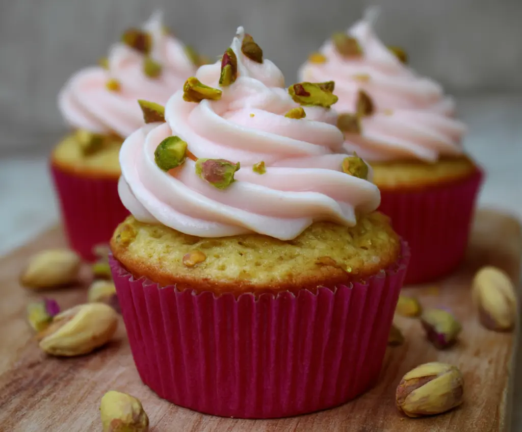 Delicious honey pistachio rosewater cupcakes topped with pistachios and rose petals.