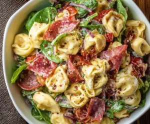 Salami and mozzarella tortellini pasta salad with fresh herbs served in a bowl.