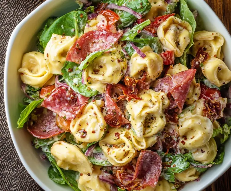 Salami and mozzarella tortellini pasta salad with fresh herbs served in a bowl.