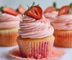 Delicious strawberry cupcakes topped with fresh strawberries and whipped cream, perfect for dessert or special occasions.